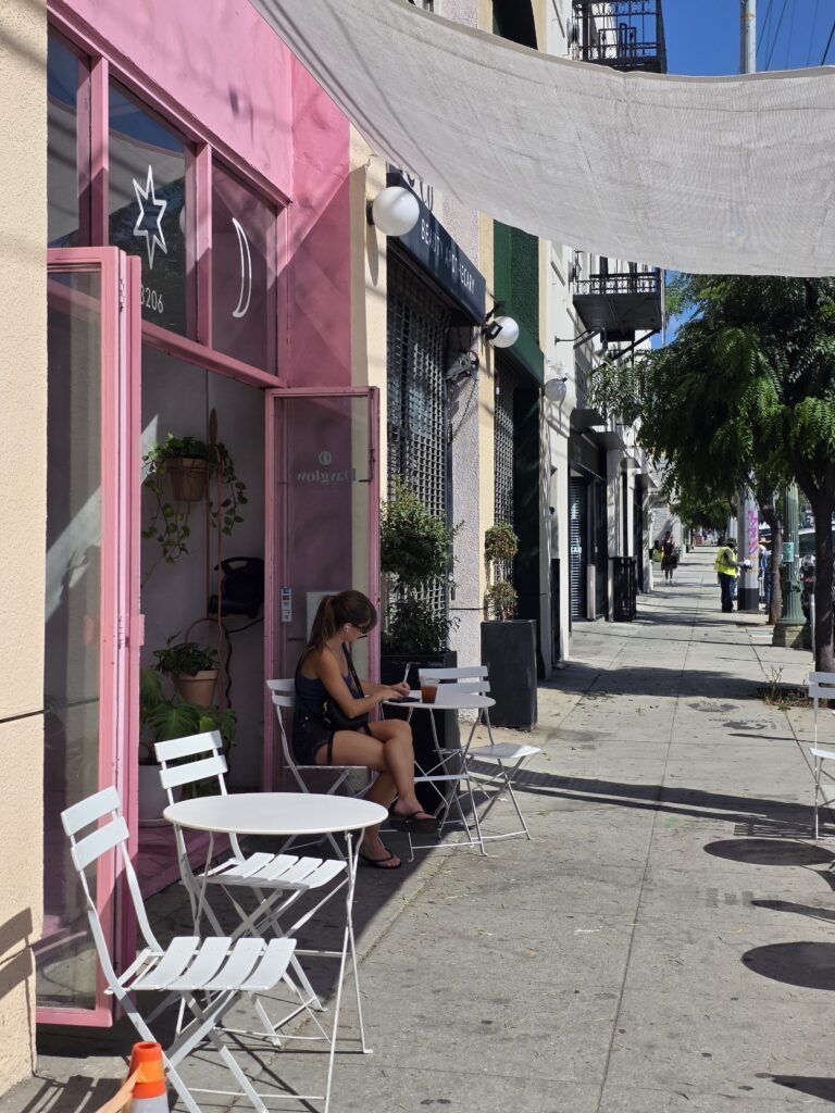A young women reading at a table outside of Day Glow in Silver Lake