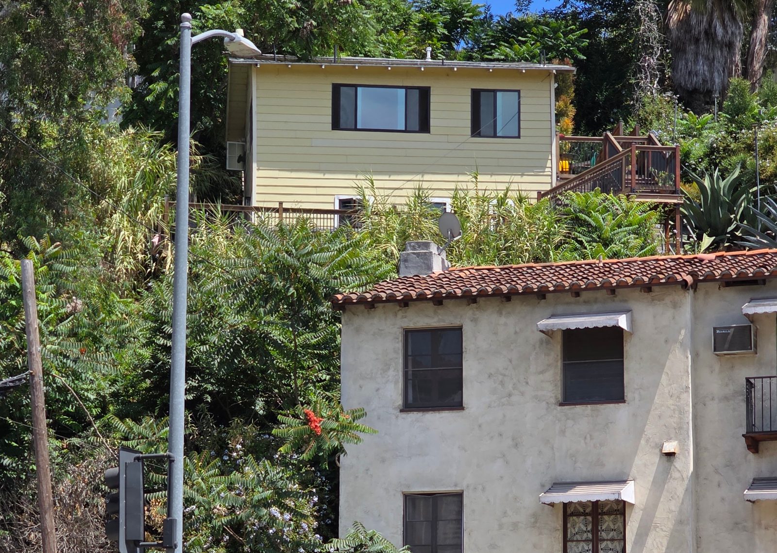 Yellow hillside house above a Spanish style stucco building with a red tile roof in Echo Park, Los Angeles