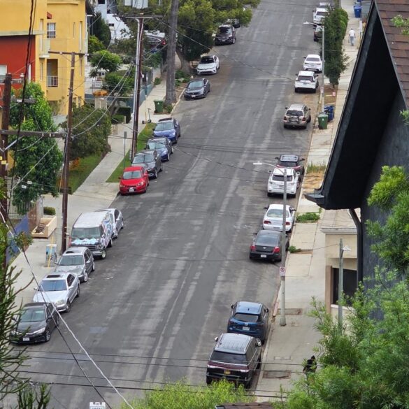 Steep residential street in Echo Park, Los Angeles, lined with parked cars and apartment buildings, seen from above